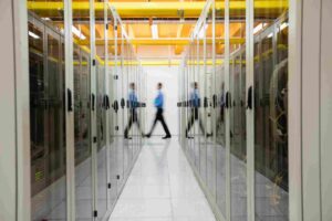 Técnico caminando por un pasillo de racks en un data center, representando infraestructura de cloud privado para IA empresarial.