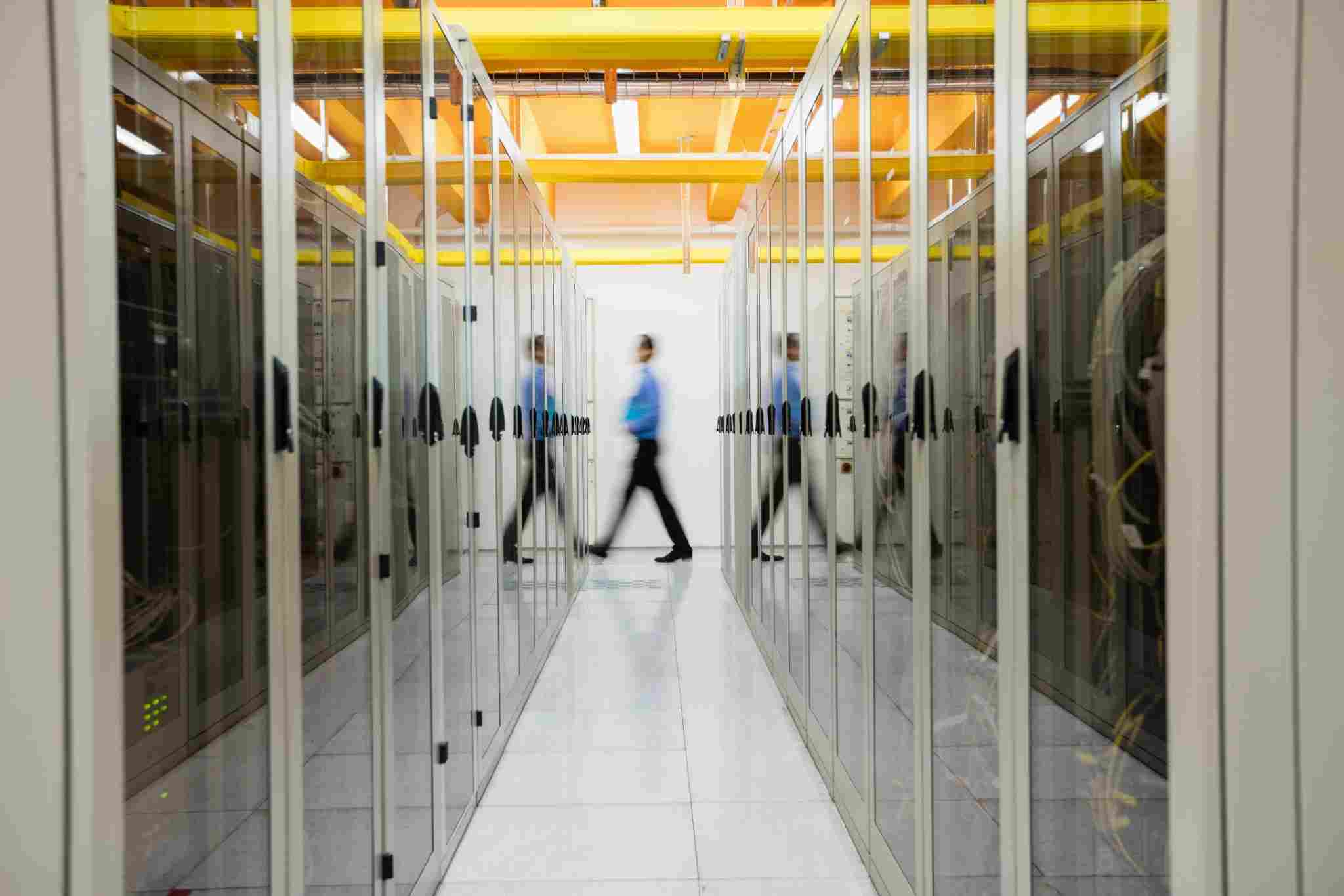Técnico caminando por un pasillo de racks en un data center, representando infraestructura de cloud privado para IA empresarial.